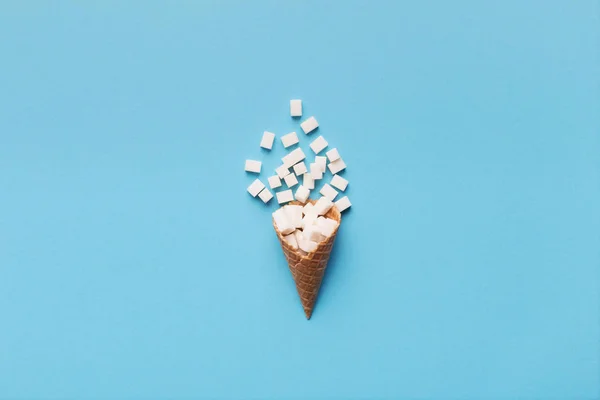 Cono gelato con cubetti di zucchero su sfondo blu — Foto Stock