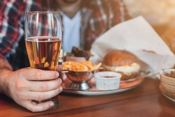 Homem descansando, bebendo cerveja e comendo hambúrguer no pab — Fotografia de Stock