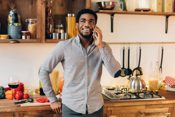 Młody czarny człowiek rozmowy na telefon komórkowy w kuchni — Zdjęcie stockowe