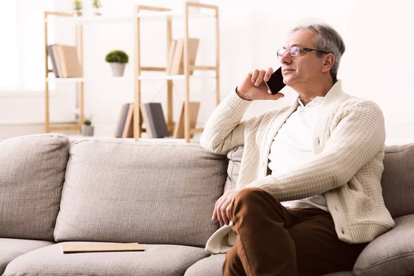Handsome old man talking on phone at home