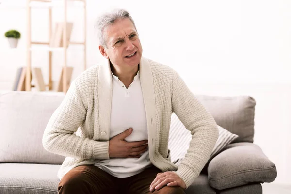 Terrible stomachache. Senior man hugging his belly, suffering from pain — Stock Photo, Image