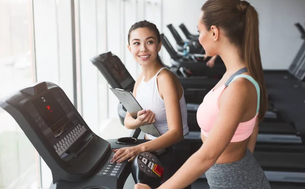 Coach discutiendo plan de entrenamiento con chica en la cinta de correr — Foto de Stock