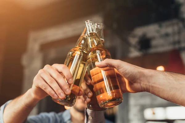 Homens batendo garrafas de cerveja juntos no bar — Fotografia de Stock