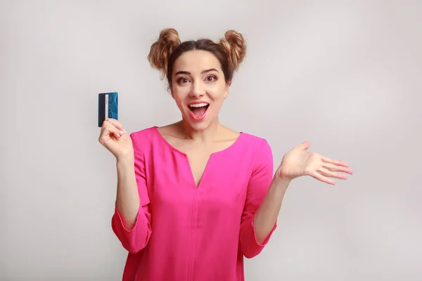灰色の背景の上クレジット カードで驚きの若い女性 — ストック写真