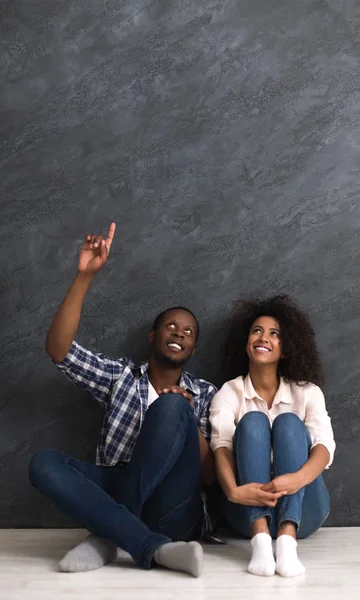 Joyeux couple assis sur le sol dans une pièce vide, espace de copie — Photo