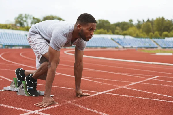 Fit afro-american runner in starting position on stadium — Stock Photo, Image