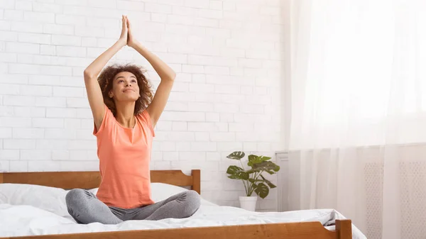African-american woman meditating on bed in bedroom — Stock Photo, Image