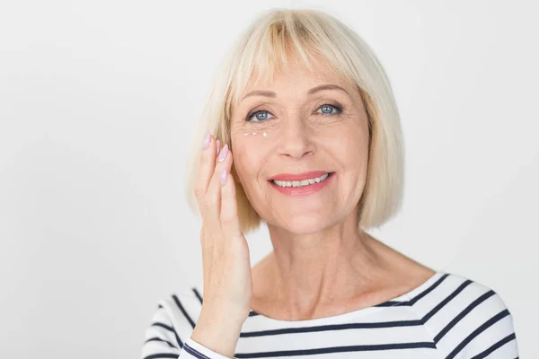 Felice donna anziana che applica crema occhi anti-rughe — Foto Stock