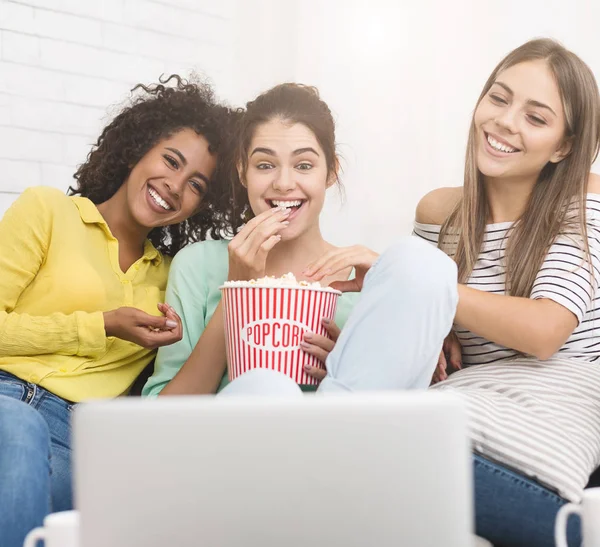 Girls watching comedy movie and eating popcorn at home