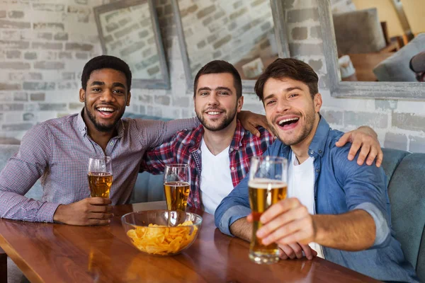 Mannen roosteren met bier, zittend in bar — Stockfoto