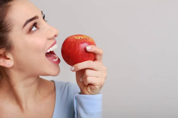 健康的な食事。背景に赤いリンゴをかむ女性 — ストック写真