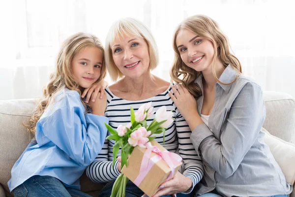 Жіноче покоління. Бабуся з подарунками, мама і дочка обіймають бабусю — стокове фото