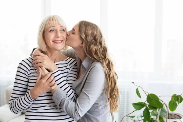 Mujer joven besando a su madre en la mejilla —  Fotos de Stock