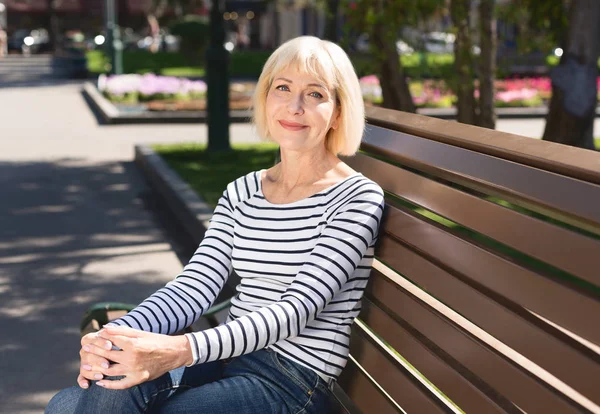 Senior mulher relaxante no banco no parque da cidade — Fotografia de Stock