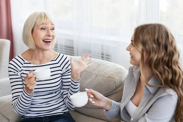 Mãe madura feliz e filha bebendo café e conversando — Fotografia de Stock