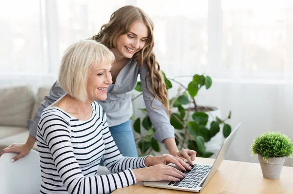 Daughter teaching mother to use laptop at home — Stock Photo, Image