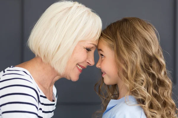 Büyükanne ve torunu dokunmadan kendi alınlarına, yan görünüm