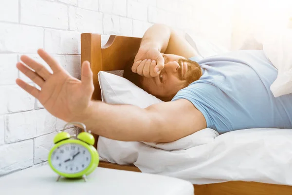 Man awakened by alarm clock in bed at morning time — Stock Photo, Image