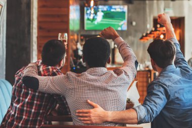 Üç adam futbol spor bar, TV izlerken arkadan görünüm