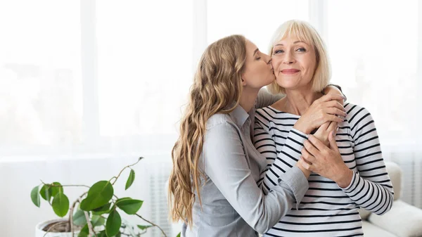 Jovem filha beijando mãe sênior na bochecha — Fotografia de Stock