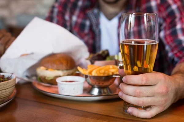 Hombre bebiendo cerveza y comiendo hamburguesa en pab — Foto de Stock