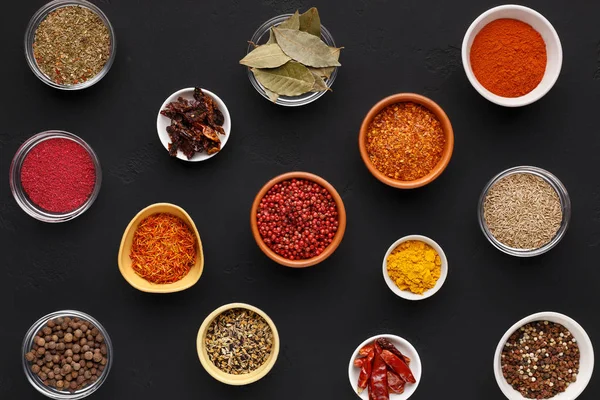 Sortiment av kryddor i skålar på svart bakgrund — Stockfoto