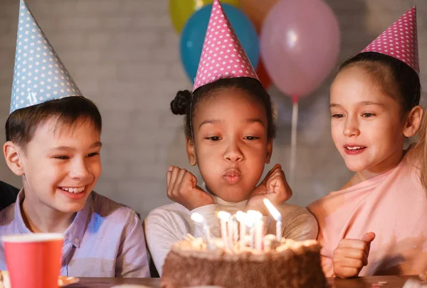 Девушка задувает свечи на торте, празднует день рождения — стоковое фото