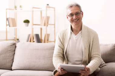 Olgun adam dijital tablet, kullanma kameraya bakıyor