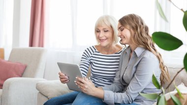 Kıdemli anne ve kızı video izlerken tablet, kullanma