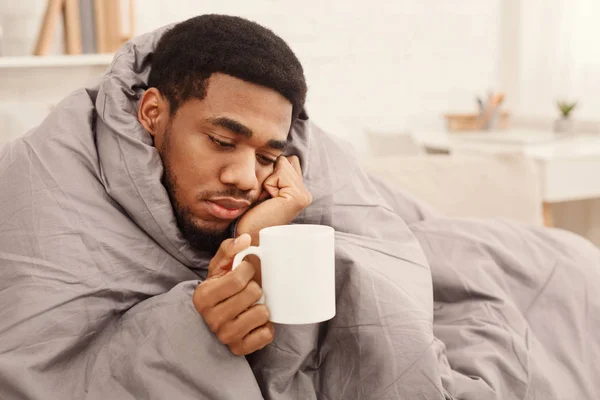 Homem negro frio com gripe envolto em manta quente — Fotografia de Stock