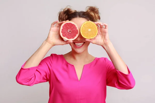 Woman covering eyes with citrus fruits, grey background — Stockfoto