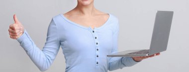 Dizüstü bilgisayar ve gösteren başparmak tutan kadın