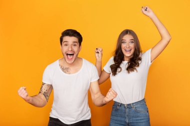 Couple clenching fists like winners over yellow background clipart
