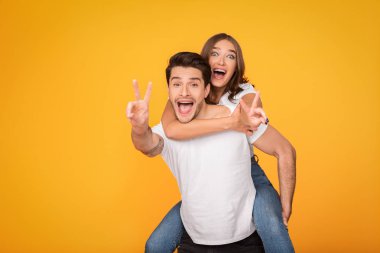 Man giving piggyback ride to woman, showing peace signs