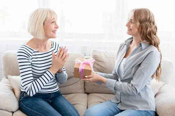 Young woman congratulating her senior mother with gift box — Stock Photo, Image