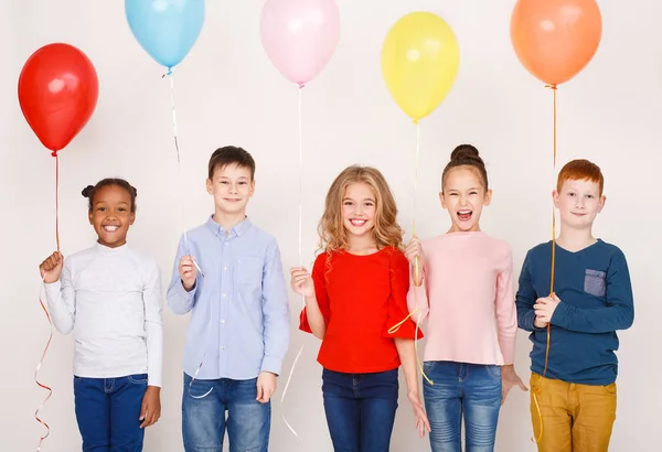 Группа детей с разноцветными воздушными шарами над стеной — стоковое фото