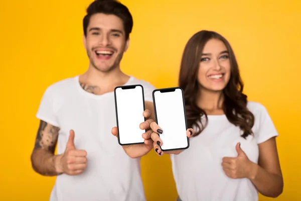 Lässiges Paar zeigt Smartphones mit leeren Bildschirmen — Stockfoto