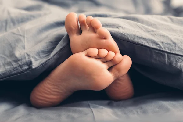 Mujer hermosos pies bajo la manta en la cama —  Fotos de Stock