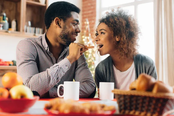 Joven pareja negra alimentándose mutuamente en la cocina —  Fotos de Stock