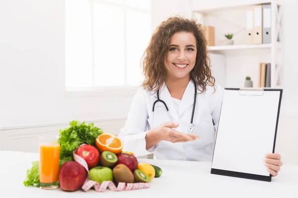 Nutricionista mujer señalando en portapapeles en blanco en la oficina —  Fotos de Stock