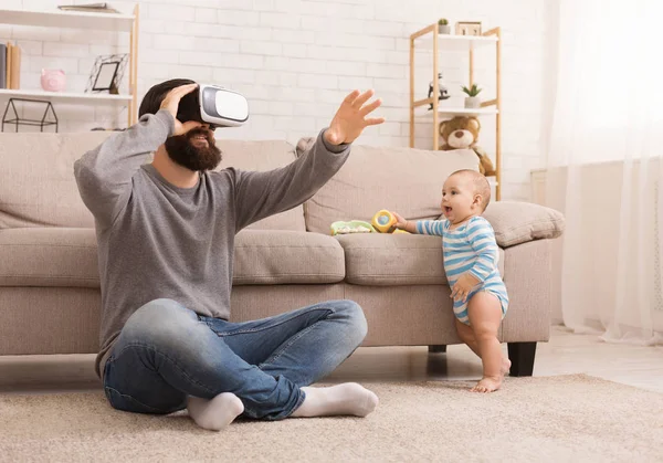Padre usando auriculares de realidad virtual, sentado con el bebé — Foto de Stock
