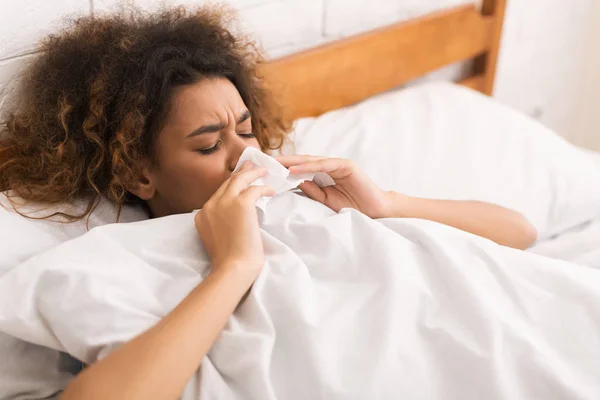 Giovane donna malata soffiando il naso a letto — Foto Stock