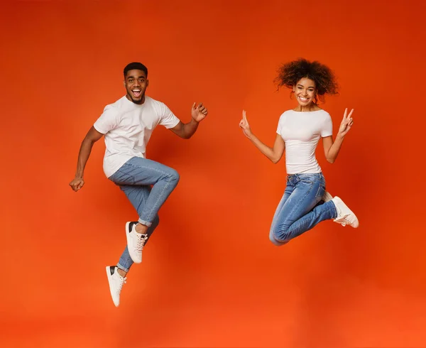 Couple noir excité sautant sur fond orange — Photo