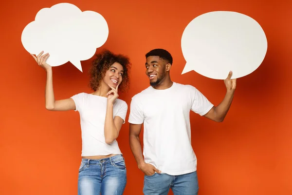 Young black couple holding speech bubbles on orange background — Stock Photo, Image