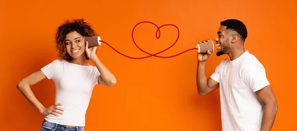 Joven pareja negra con lata de teléfono sobre fondo naranja — Foto de Stock