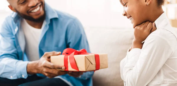 Happy girl receiving gift from father at home — Stock Photo, Image