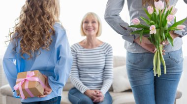 Küçük kız ve annesi çiçekler ve Büyükanne için hediye kutusunu gizleme