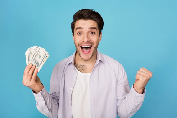 Muž drží dolarů a slaví úspěch nad pozadím — Stock fotografie