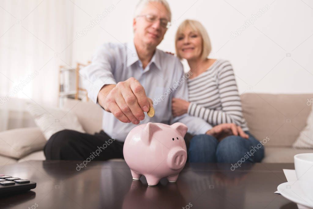 Senior couple saving money in piggybank at home