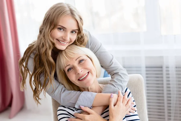 Filha jovem abraçando sua mãe sênior com amor — Fotografia de Stock